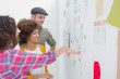 Young team of designers working together and pointing at a wall
