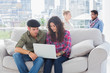 Pair of workers working on a laptop on a couch
