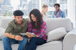 Pair of workers working on a tablet computer on a couch