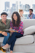 Smiling workers working on a tablet computer on a couch