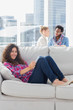 Cheerful worker using tablet pc while laying on a couch