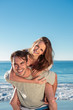 Man giving a piggy back to his girlfriend during the summer