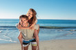 Man giving a piggy back to his girlfriend on the beach