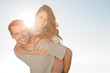 Happy man giving a piggy back to his girlfriend 
