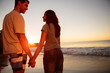 Couple smiling and walking hand in hand on the beach