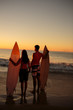 Lovers hand in hand holding surfboards on the beach