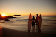 Lovers hand in hand with surfboards looking at the sunset