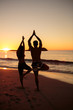 Silhouettes of people doing yoga under the sunset