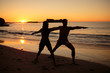 Silhouettes of people practicing yoga under the sunset