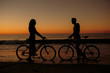 Silhouettes of people facing each other on bicycles 