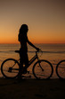 Silhouette of woman on his bike on the beach
