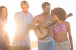 Handsome man playing guitar on the beach