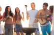 Happy friends preparing barbecue on the beach