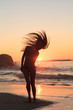 Woman standing on the beach tossing her hair
