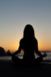 Silhouette of woman doing yoga on the beach