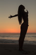 Silhouette of an attractive woman spreading her arms on the beach