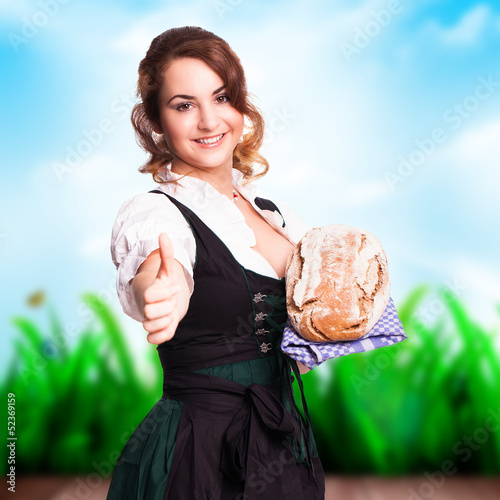 Photo: junge Frau im Dirndl bietet ein Brot an junge Frau im Dirndl bietet ein Brot an