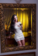 Sensual  womaan in white dress looking mirror with a wine glass