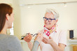 Optiker bietet Frau Brille an