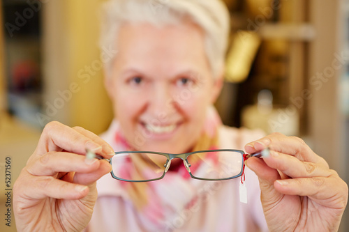 Photo: Seniorin hält Brille beim Optiker Seniorin hält Brille beim Optiker