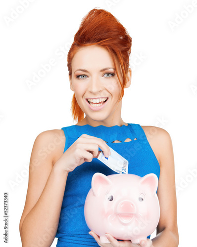 Photo: woman putting cash money into piggy bank woman putting cash money into piggy bank