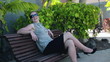 Smiling businesswoman in tourist resort sitting on the bench, st