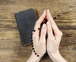 Hands holding the Bible and praying with a rosary