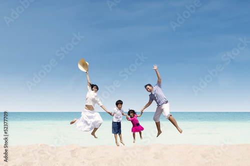 Photo: Happy family jumping at beach Happy family jumping at beach