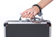 case of money in handcuffs with hand, isolated