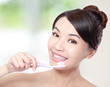 smiling woman cleaning teeth with toothbrush