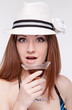 girl in a hat holding a glass near the lip,