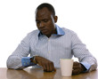 Photo: African man with cup of tea, sitting on the desk African man with cup of tea, sitting on the desk
