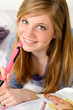 Smiling teenage girl daydreaming over her diary
