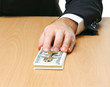Photo: Businessman sitting on the desk and holding money in a hand Businessman sitting on the desk and holding money in a hand