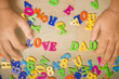 Hands of a boy putting "love dad" plastic alphabets together.