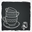 Hand drawn tea cups and a teabag on chalkboard background