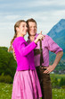 Paar in Tracht auf Wiese vor Bergpanorama