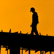 Silhouette of construction workers on scaffold working under a h