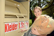 Junge Frau vor Altkleider-Container
