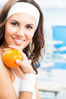Woman with orange, at fitness center
