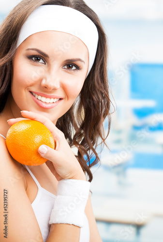 Photo: Woman with orange, at fitness center Woman with orange, at fitness center