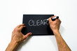 two hand writing "clear" on a black background