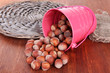 Overturned bucket with hazelnuts on wooden background