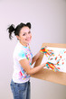Young pretty painter with hands in paint, on gray background