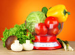 Fresh vegetables in scales on table on orange background