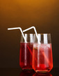Two cherry cocktails with ice on dark orange background