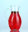Cherry drink in pitcher on blue background.
