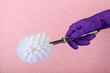 Toilet brush in hand on pink background