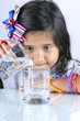 Pequeña niña vierte agua de un vaso a otro
