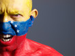 Man face painted with venezuelan flag, angry expression.